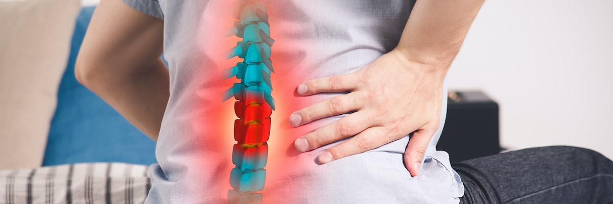 Person holding lower back with a red-highlighted spine model indicating back pain.